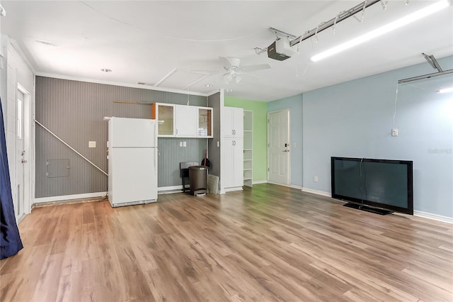 unfurnished living room with baseboards, attic access, light wood-type flooring, and a ceiling fan