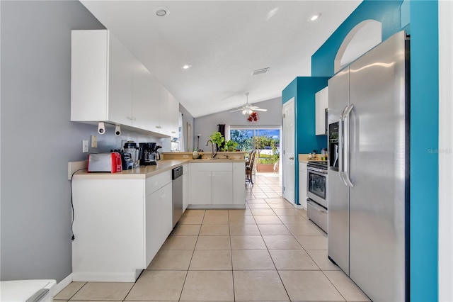 kitchen featuring light tile patterned floors, white cabinets, appliances with stainless steel finishes, and a peninsula