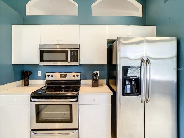 kitchen featuring appliances with stainless steel finishes, white cabinets, and light countertops