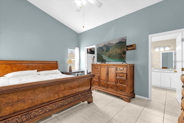 bedroom featuring light tile patterned flooring, vaulted ceiling, a spacious closet, ensuite bathroom, and a textured ceiling