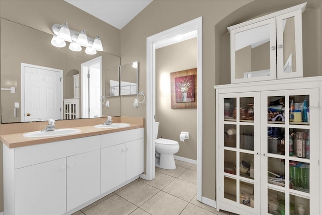 bathroom with tile patterned flooring, double vanity, toilet, and a sink