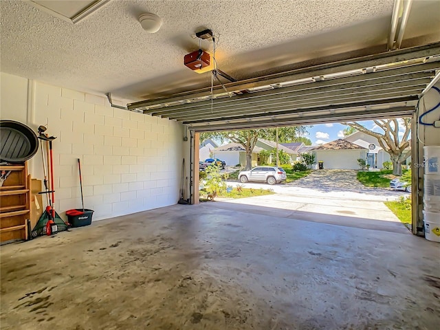 garage featuring a garage door opener and concrete block wall