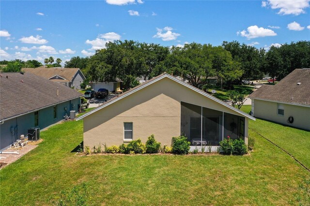 exterior space with cooling unit, a yard, a sunroom, and stucco siding