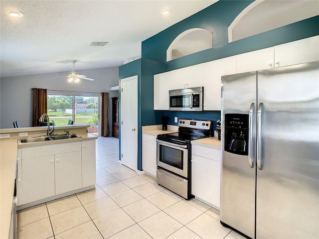 kitchen with light tile patterned floors, a sink, stainless steel appliances, vaulted ceiling, and light countertops