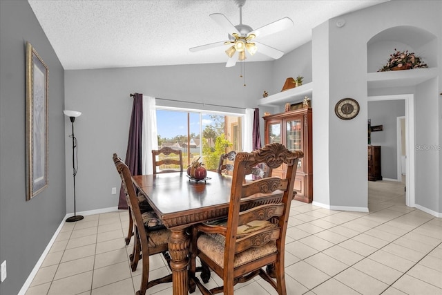 dining area with light tile patterned floors, a ceiling fan, baseboards, vaulted ceiling, and a textured ceiling