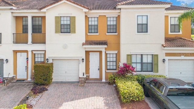 multi unit property with a tile roof, decorative driveway, an attached garage, and stucco siding