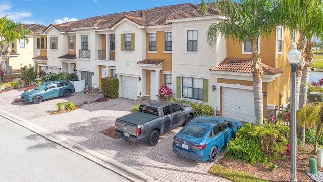 townhome / multi-family property featuring stucco siding, a tile roof, decorative driveway, a residential view, and a garage