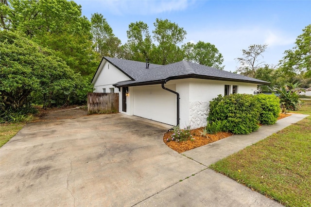 view of home's exterior with fence, driveway, an attached garage, a shingled roof, and stucco siding