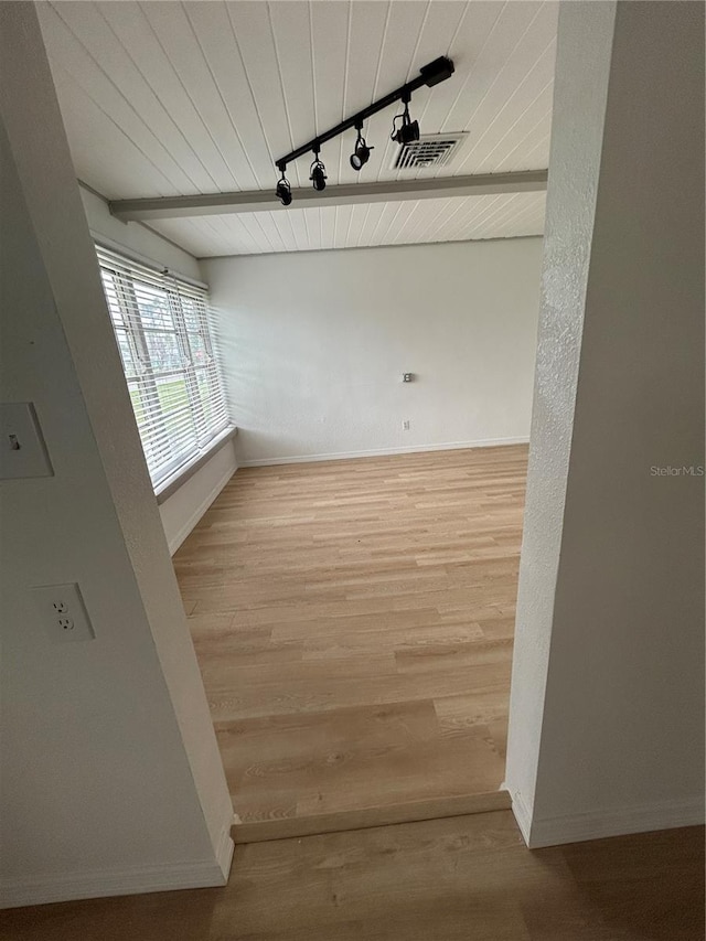 empty room featuring wood finished floors, baseboards, visible vents, track lighting, and wood ceiling