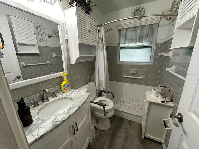 full bathroom featuring vanity, wood finished floors, a stall shower, tile walls, and toilet