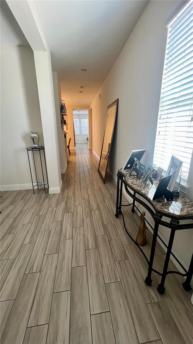 hall with an upstairs landing, baseboards, and wood finish floors