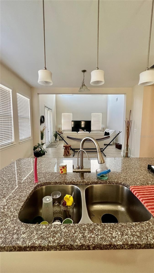 kitchen with dark stone countertops, pendant lighting, and a sink