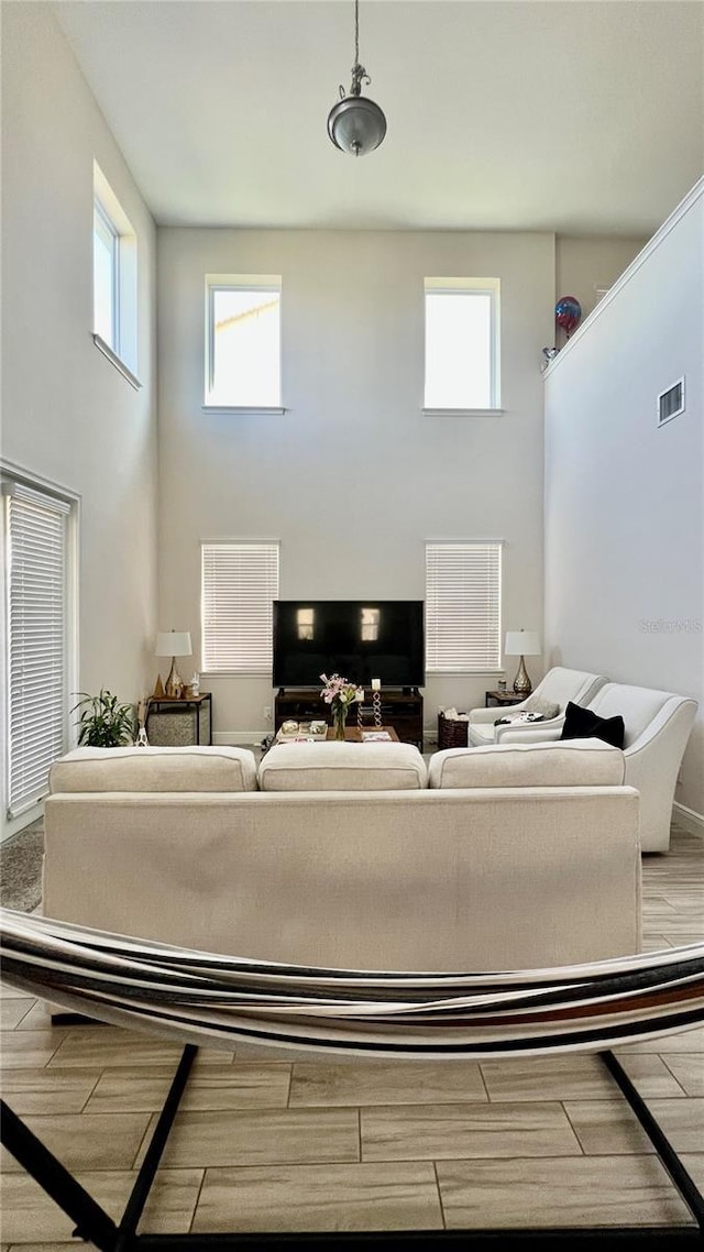 living room with wood finished floors, visible vents, and a towering ceiling