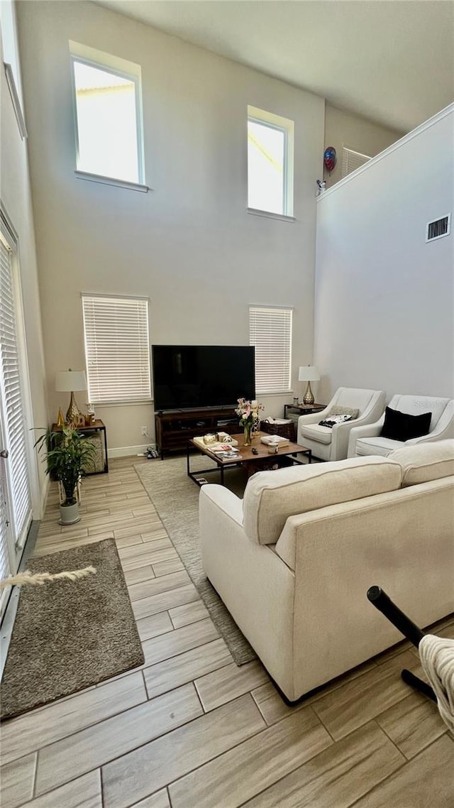 living area featuring visible vents, a towering ceiling, and wood tiled floor