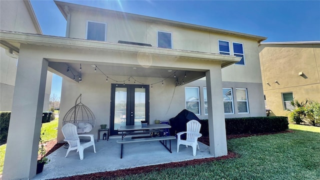 back of property featuring a patio area, stucco siding, french doors, and a yard