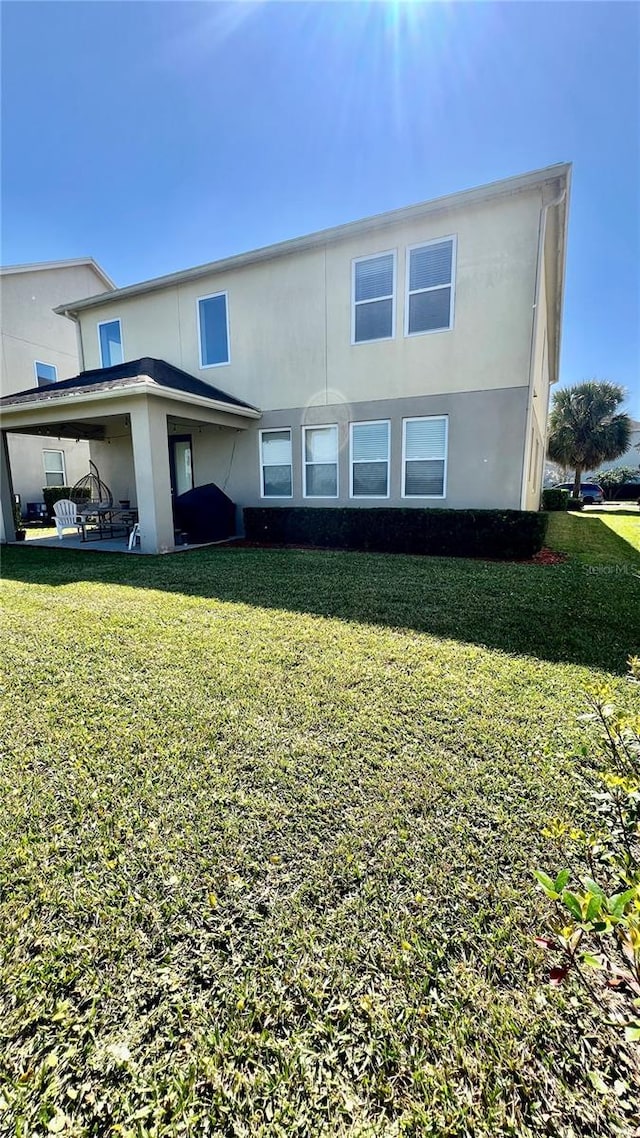 view of front facade with a front lawn, a patio area, and stucco siding