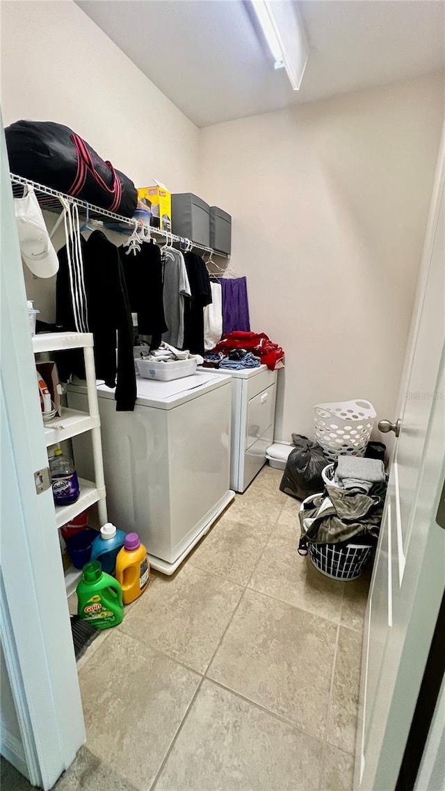 clothes washing area with laundry area, light tile patterned floors, and washer and clothes dryer