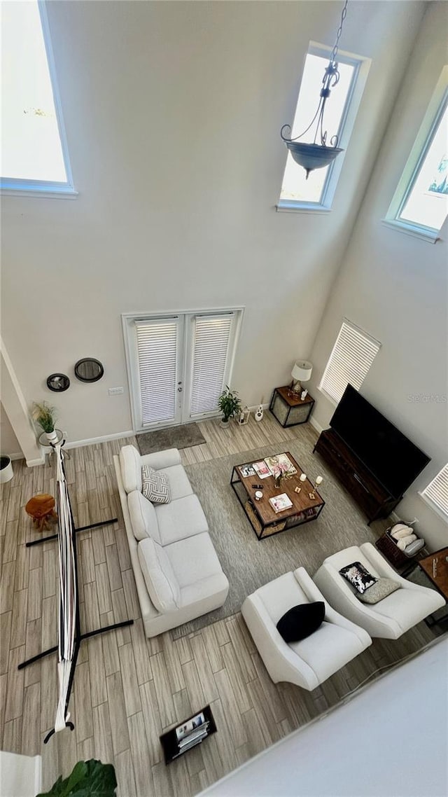 living room with a healthy amount of sunlight, visible vents, a towering ceiling, and wood tiled floor