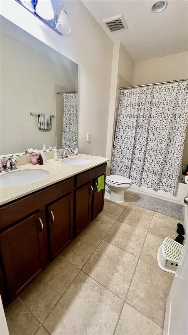 bathroom featuring double vanity, visible vents, toilet, and a sink