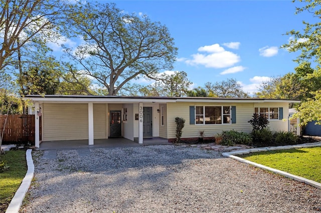 single story home featuring an attached carport, fence, and driveway