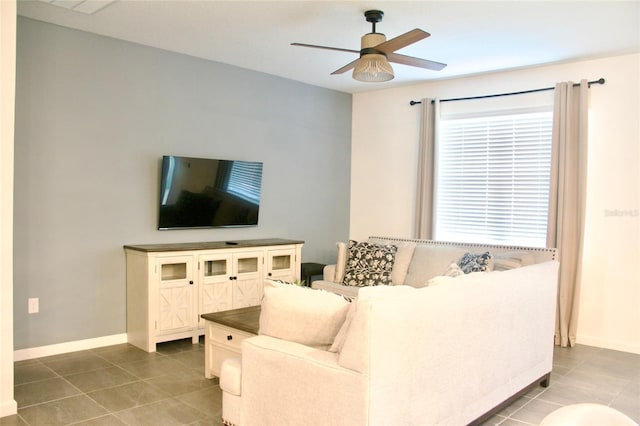 living area with baseboards, ceiling fan, and tile patterned flooring