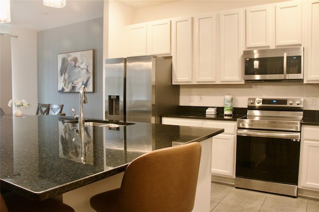 kitchen featuring a breakfast bar, a sink, appliances with stainless steel finishes, white cabinets, and light tile patterned floors