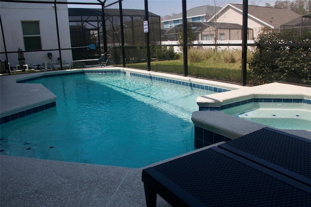 view of pool with a patio area, glass enclosure, and a pool with connected hot tub