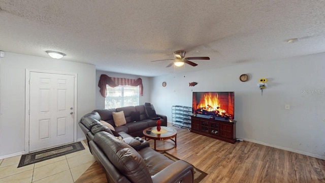 living area with baseboards, light wood-style floors, ceiling fan, and a textured ceiling