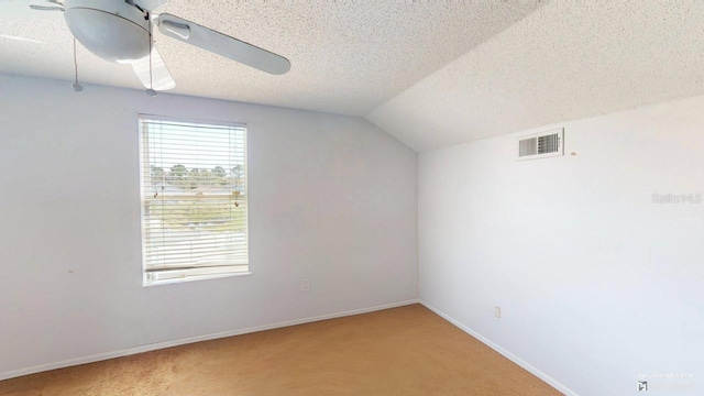 additional living space with visible vents, light colored carpet, a textured ceiling, and ceiling fan