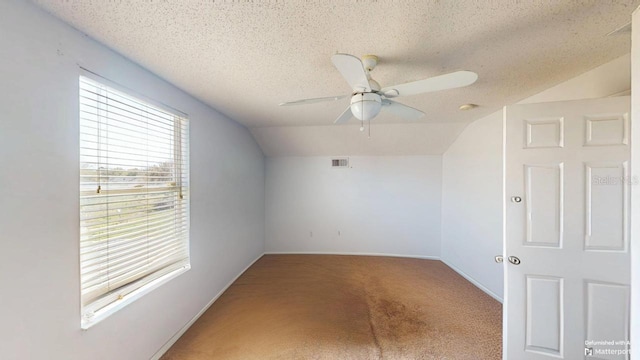 additional living space with a ceiling fan, visible vents, vaulted ceiling, a textured ceiling, and carpet flooring