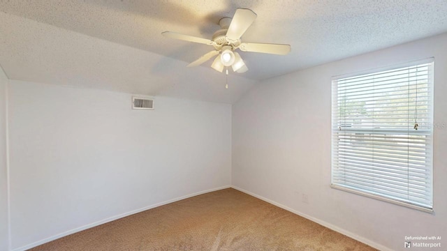 carpeted spare room with visible vents, baseboards, vaulted ceiling, a textured ceiling, and a ceiling fan