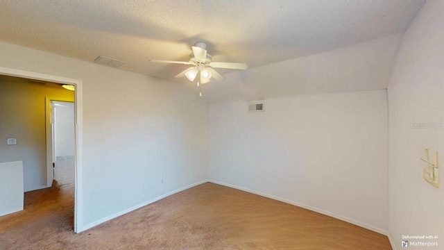 carpeted spare room featuring visible vents, baseboards, a textured ceiling, and a ceiling fan