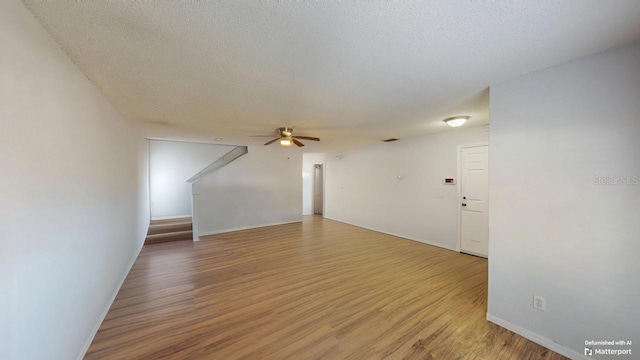 unfurnished living room with light wood-type flooring, baseboards, a textured ceiling, and a ceiling fan