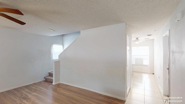 interior space with stairway, baseboards, ceiling fan, and light wood-style flooring