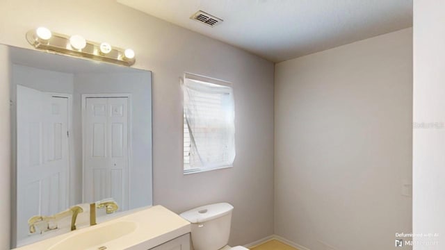 bathroom featuring visible vents, toilet, and vanity