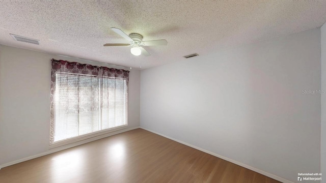 empty room with visible vents, a textured ceiling, and wood finished floors