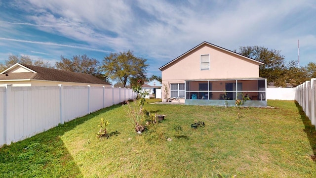 back of house featuring a lawn, a fenced backyard, a sunroom, and stucco siding