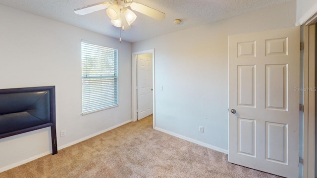 unfurnished bedroom featuring a ceiling fan, carpet, baseboards, and a textured ceiling