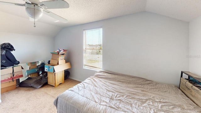 bedroom with a textured ceiling, light colored carpet, a ceiling fan, and vaulted ceiling