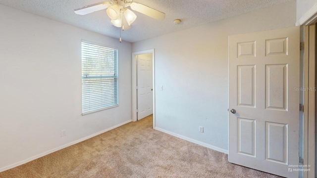 unfurnished room with a ceiling fan, baseboards, a textured ceiling, and carpet flooring