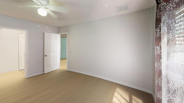 unfurnished bedroom with visible vents, baseboards, wood finished floors, and a ceiling fan