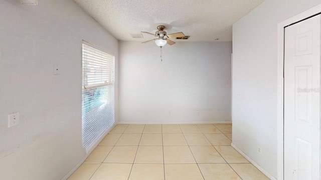 spare room featuring baseboards, visible vents, light tile patterned flooring, ceiling fan, and a textured ceiling