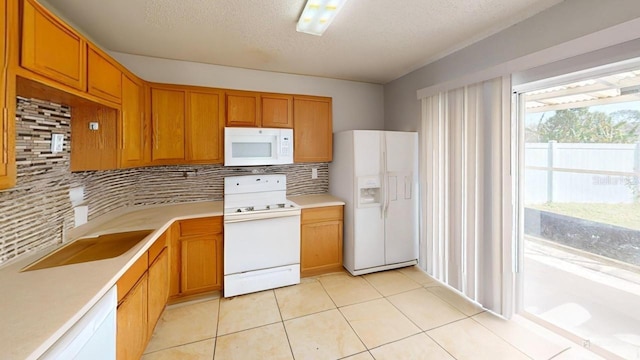 kitchen with white appliances, brown cabinetry, light tile patterned flooring, decorative backsplash, and light countertops