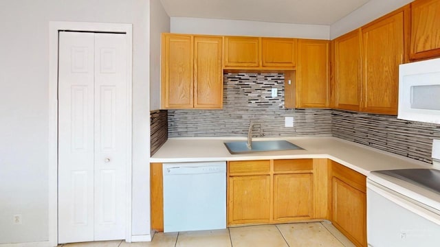 kitchen with light tile patterned floors, decorative backsplash, white appliances, and a sink