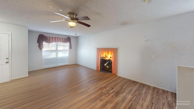 unfurnished living room featuring baseboards, a textured ceiling, ceiling fan, and wood finished floors