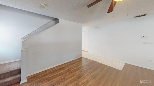 spare room featuring stairway, a textured ceiling, visible vents, and wood finished floors