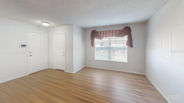 unfurnished room with wood finished floors, baseboards, and a textured ceiling