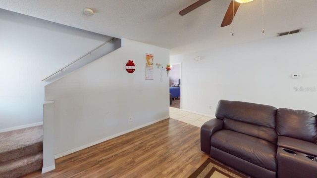 living room featuring visible vents, a ceiling fan, a textured ceiling, wood finished floors, and baseboards