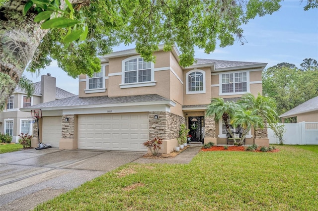 traditional home featuring fence, stucco siding, concrete driveway, a front lawn, and stone siding