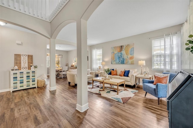 living room with baseboards, arched walkways, and wood finished floors